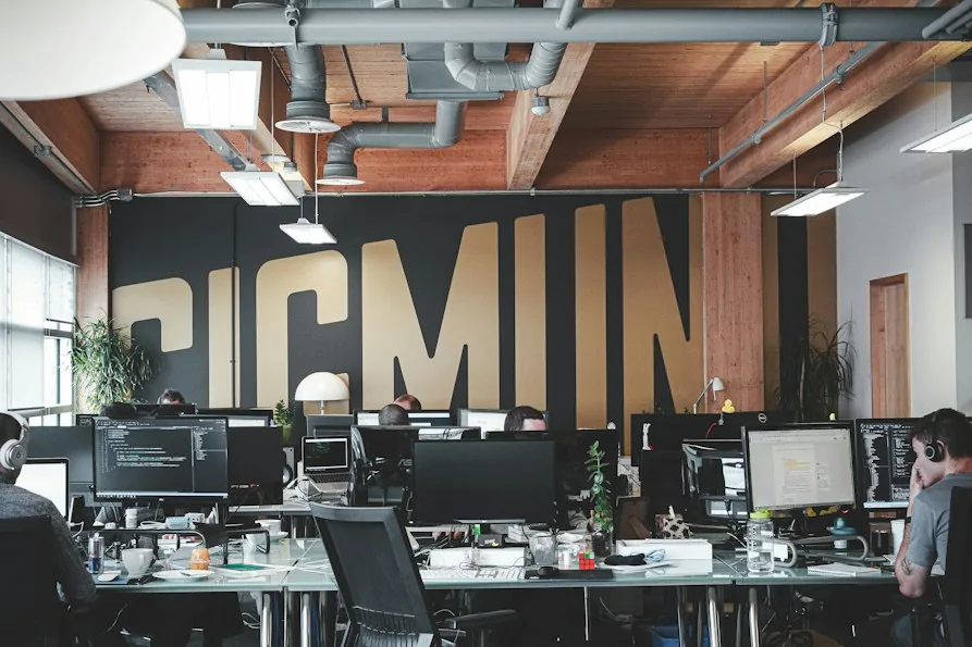 Un open space con postazioni di lavoro e una grande scritta sulla parete