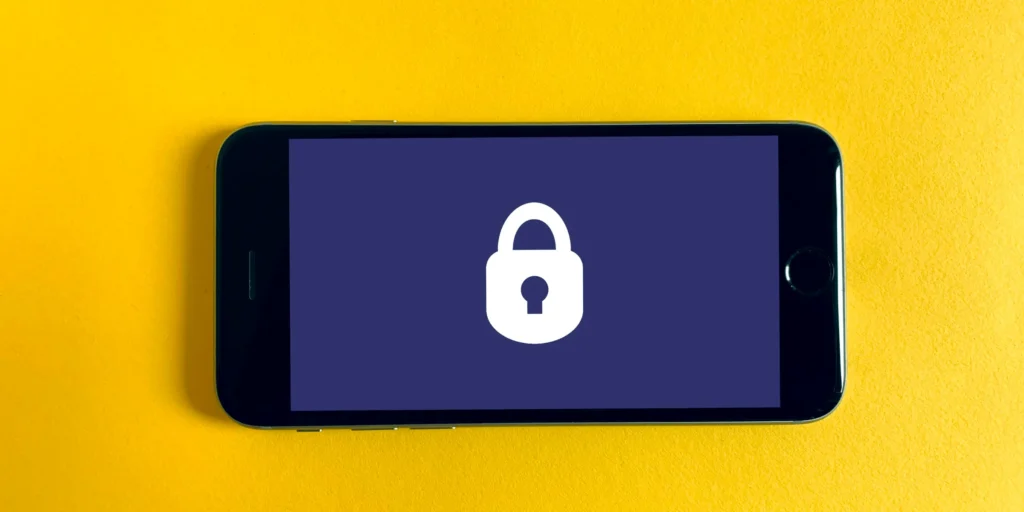 Smartphone con un lucchetto sullo schermo su fondo giallo