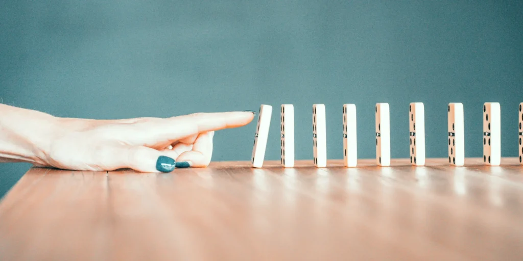 Un dito sta per spingere la prima tessera di una fila di domino