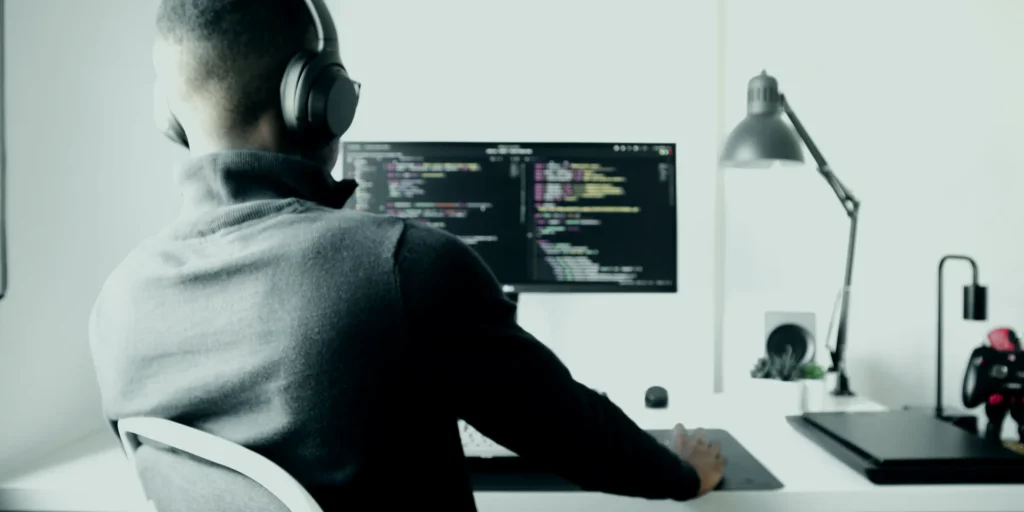 Sviluppatore con le cuffie al lavoro al computer in una stanza bianca e luminosa