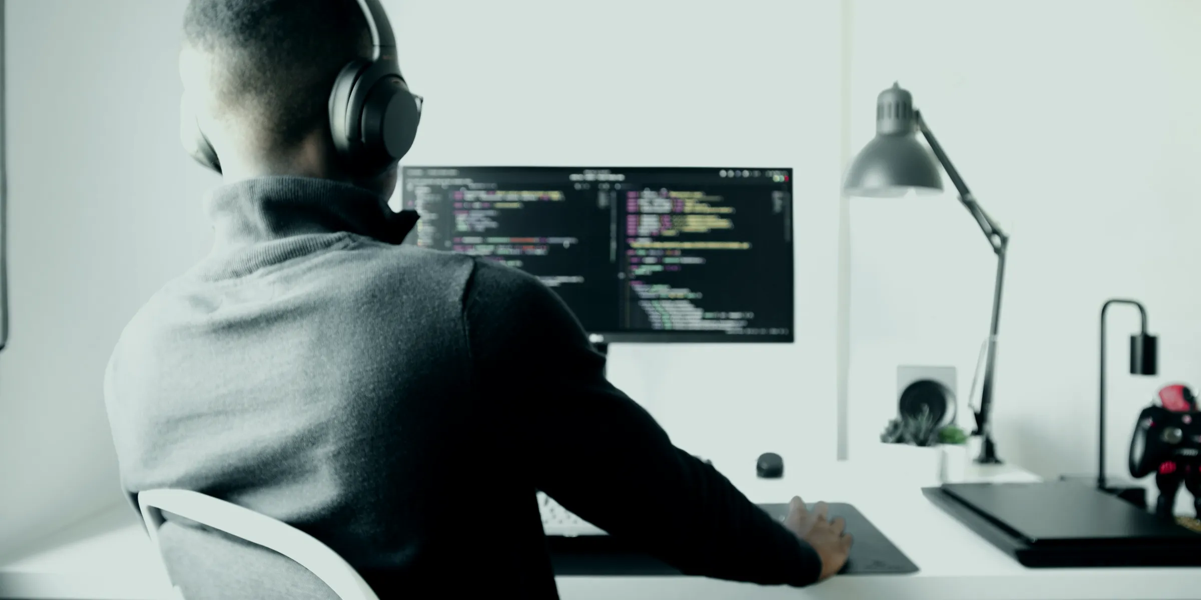 Sviluppatore con le cuffie al lavoro al computer in una stanza bianca e luminosa