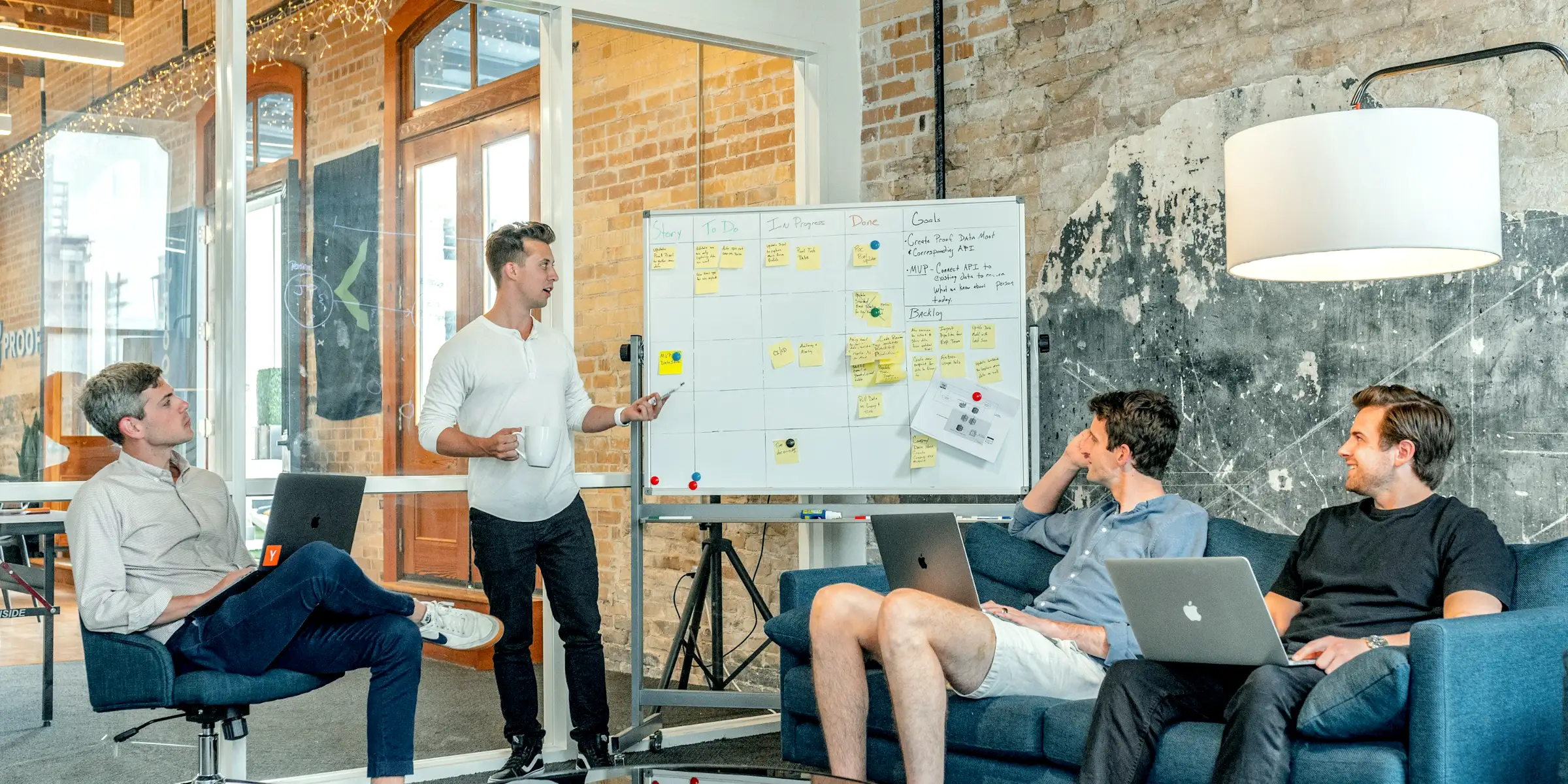 Un team con i portatili segue una presentazione alla lavagna in un loft luminoso