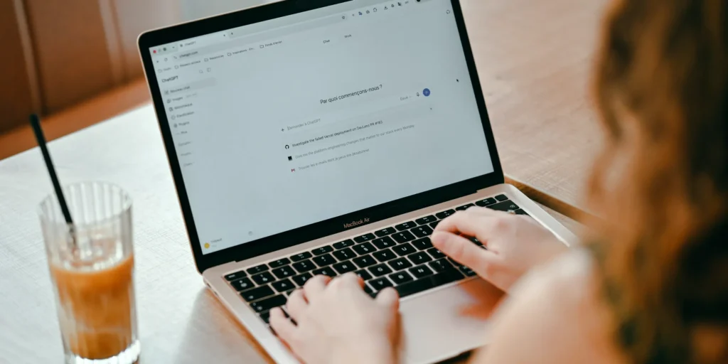 Mani che scrivono a un assistente AI su un computer portatile