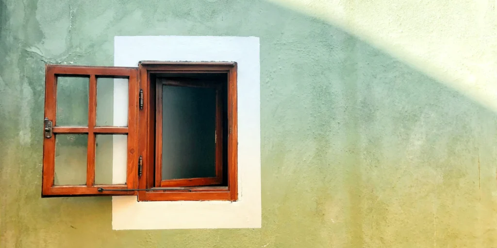 Una finestra di legno rossa aperta su un muro chiaro