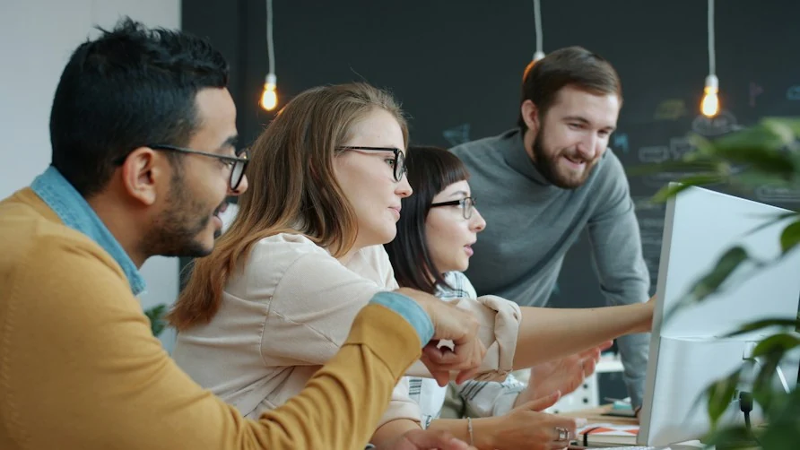 Un gruppo di colleghi guarda insieme lo schermo di un computer e ne discute