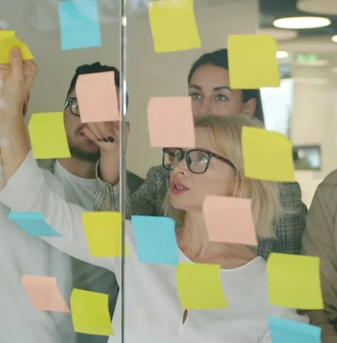 Due persone attaccano post-it colorati su una parete di vetro